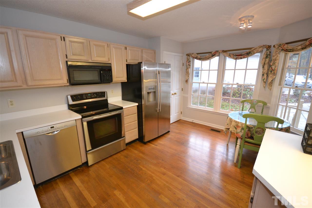 24 Renwick Court Raleigh, NC 27615 - Photo 2 of 20 a kitchen with stainless steel appliances a stove top oven a sink a refrigerator white cabinets and wooden floor