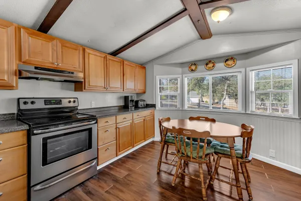 a kitchen with stainless steel appliances granite countertop wooden floors and white cabinets