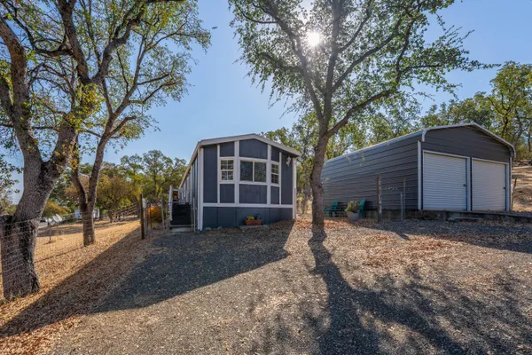 a view of a house with a yard and large tree