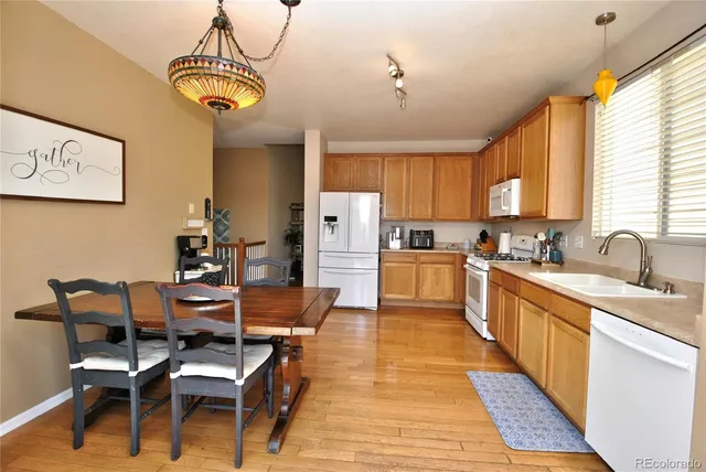 a kitchen with stainless steel appliances kitchen island granite countertop a table chairs and a refrigerator