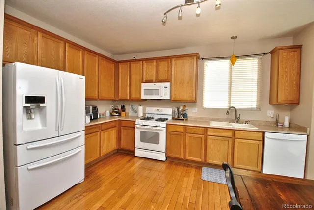 a kitchen with granite countertop appliances a sink cabinets and a large window