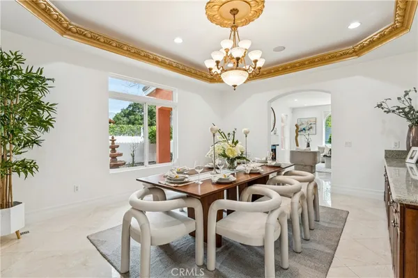 a view of a dining room with furniture a chandelier and large windows