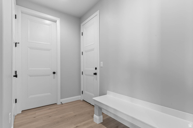 11673 South Halls Crk Road Draper, UT 84020 - Photo 18 of 22 Entryway featuring light wood-finish flooring, white paneled doors with matte black hardware, a built-in white bench, and light gray wall paint