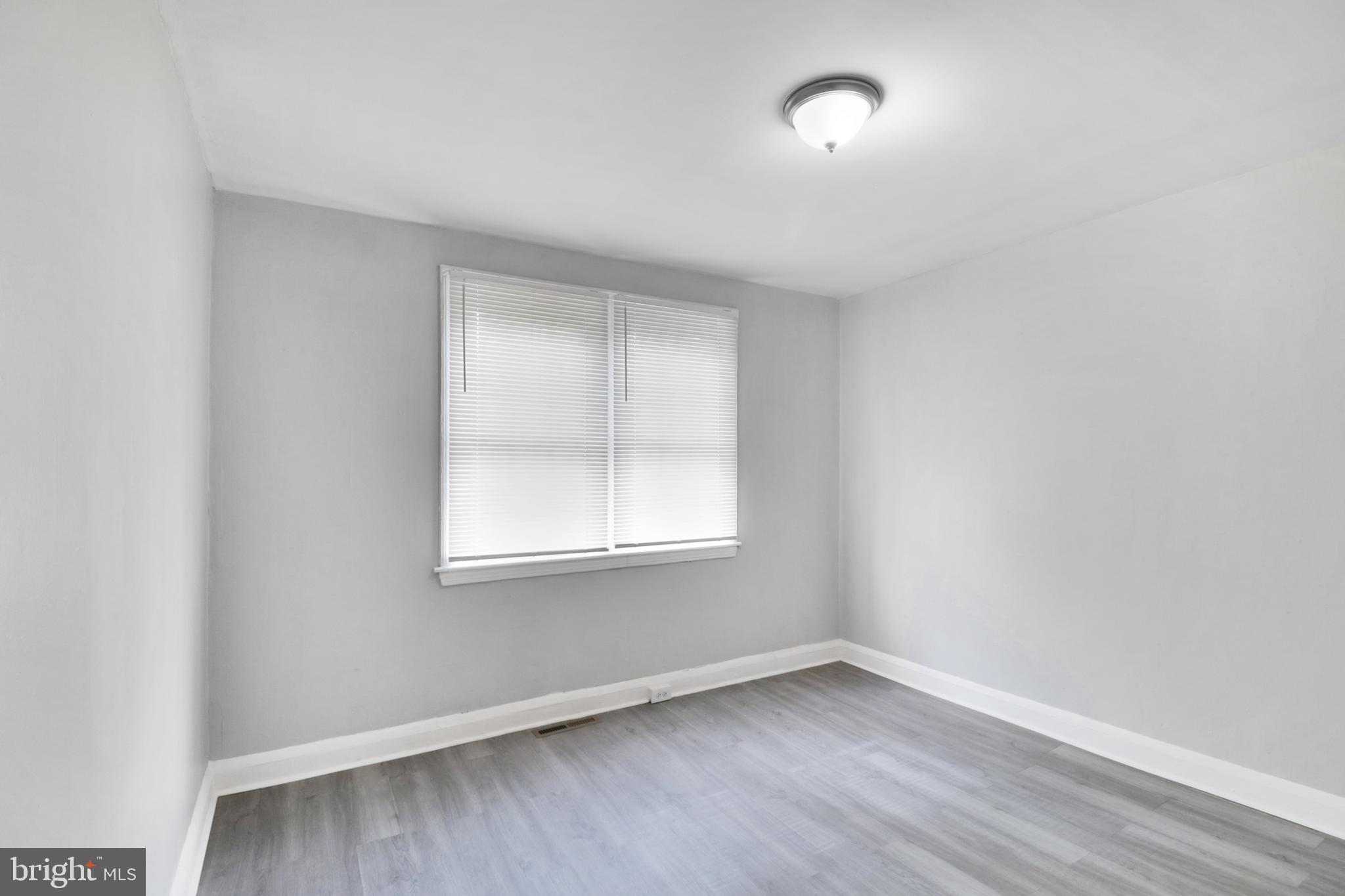 6151 Chinquapin Parkway Baltimore, MD 21239 - Photo 5 of 22 an empty room with wooden floor and windows