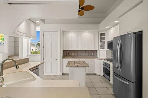 a kitchen with a refrigerator sink and white cabinets