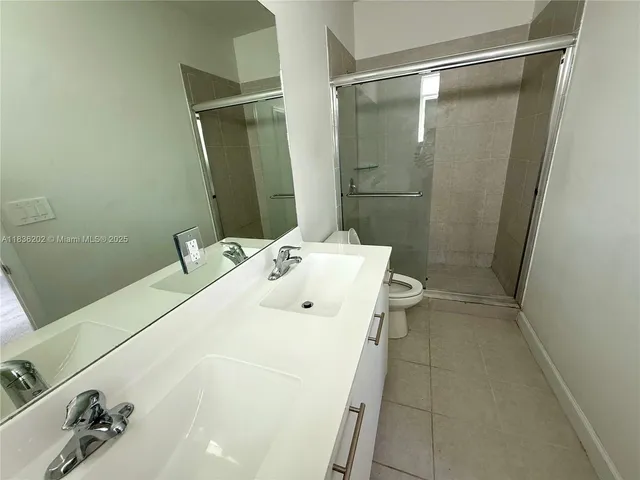 a bathroom with a sink a toilet a mirror and shower