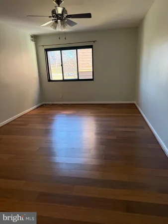 an empty room with wooden floor fan and windows