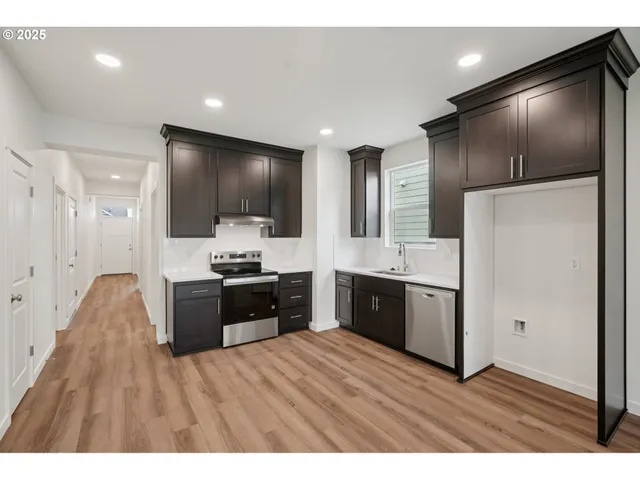 a large kitchen with a refrigerator a sink dishwasher stove and oven with wooden floor