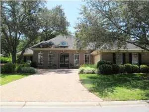 a front view of a house with a garden and trees