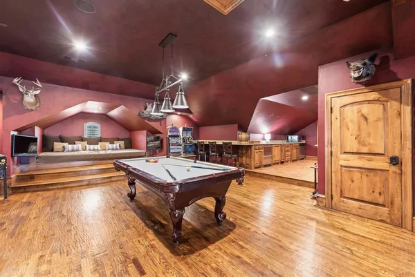 a dining hall with stainless steel appliances kitchen island granite countertop a sink dishwasher and a fireplace with wooden floor