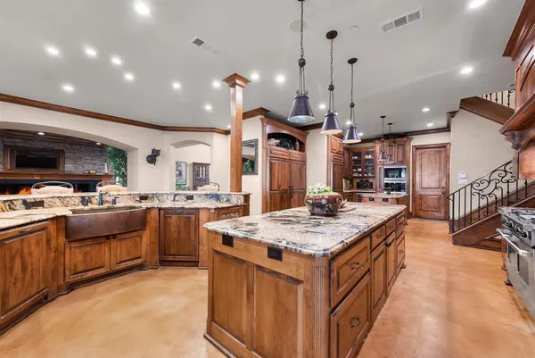 a large kitchen with kitchen island a stove a sink a oven and a refrigerator