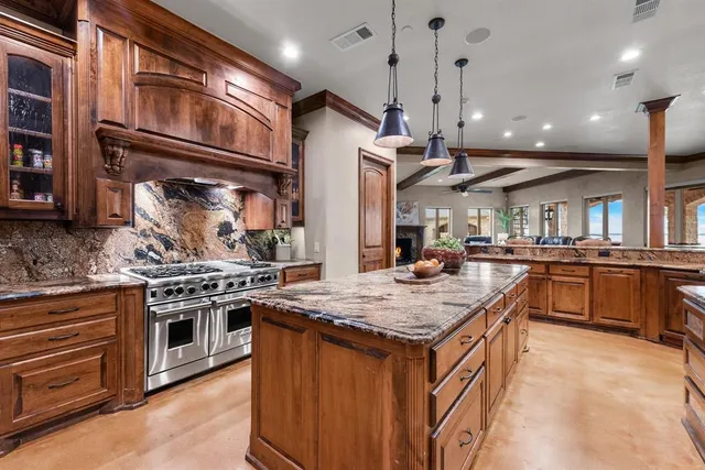 a kitchen with stainless steel appliances granite countertop a stove a sink dishwasher and a refrigerator with wooden floor