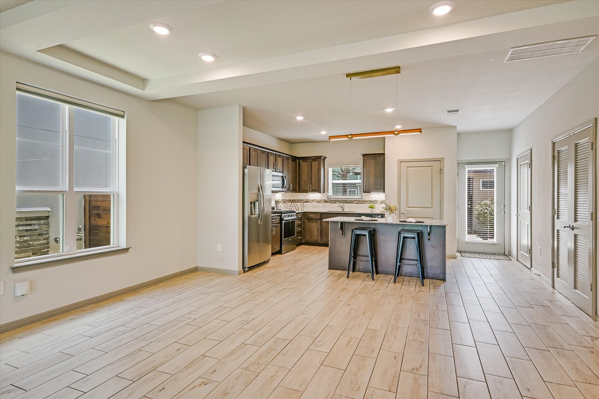 5613 Charles Merle Dr. Austin, TX 78747 - Photo 6 of 34 a kitchen with stainless steel appliances kitchen island granite countertop a stove top oven a sink dishwasher a dining table and chairs with wooden floor