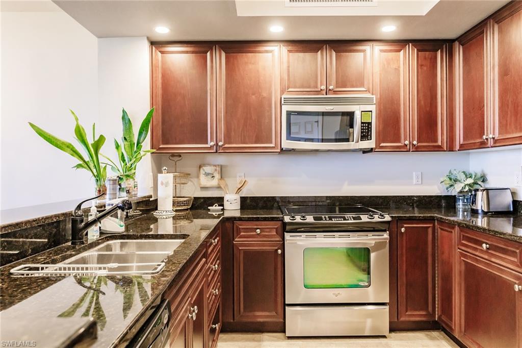 1065 Borghese Lane, Unit 1003 Naples, FL 34114 - Photo 12 of 43 a kitchen with a stove a sink and a microwave