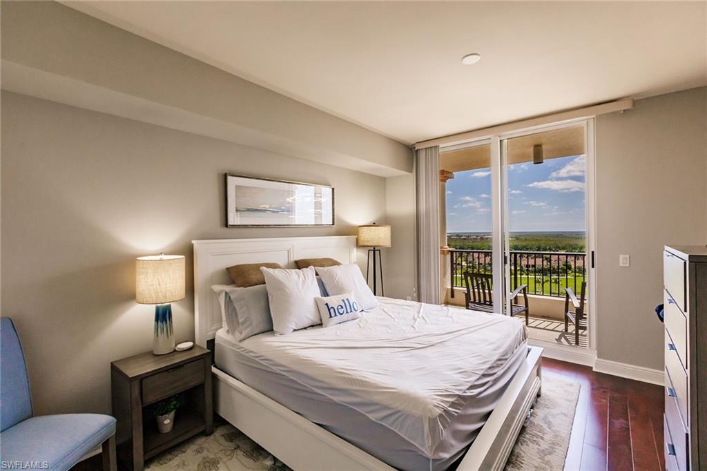 1065 Borghese Lane, Unit 1003 Naples, FL 34114 - Photo 20 of 43 a bedroom with a bed a table and a large window