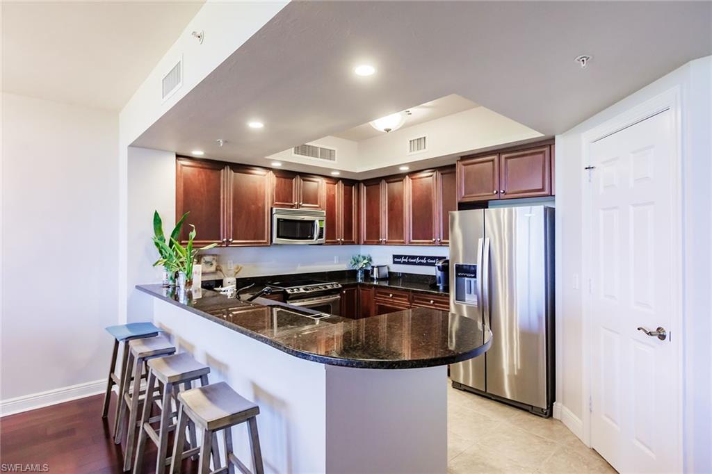 1065 Borghese Lane, Unit 1003 Naples, FL 34114 - Photo 10 of 43 a kitchen with stainless steel appliances granite countertop a sink refrigerator and cabinets