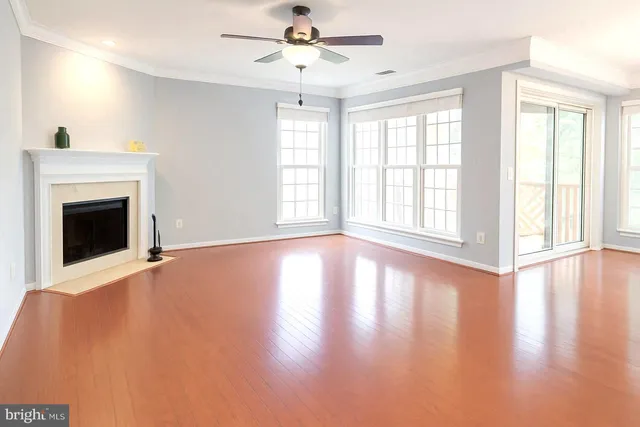 a view of an empty room with window and wooden floor