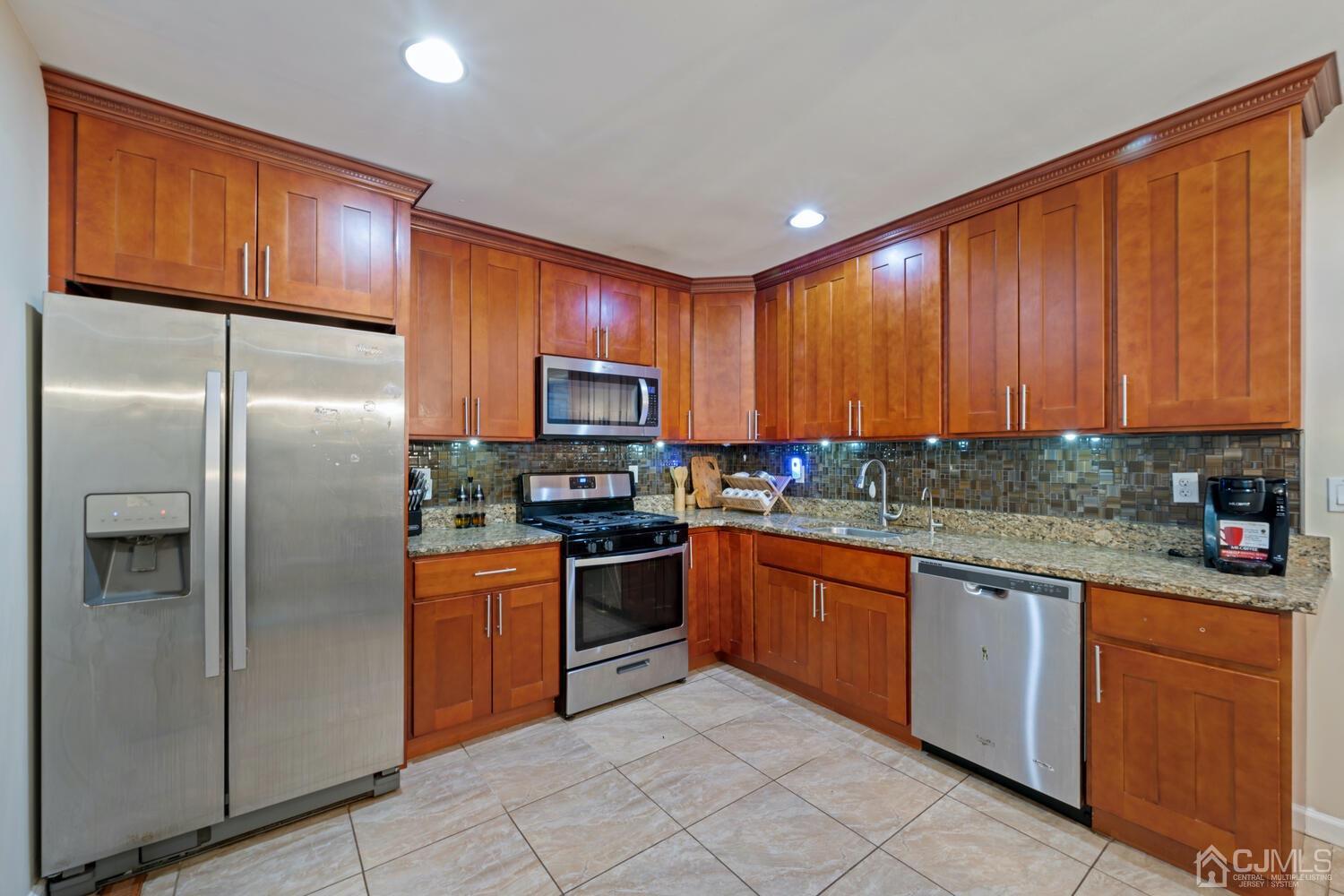 21 Kingsley Road Kendall Park, NJ 08824 - Photo 14 of 29 a kitchen with granite countertop stainless steel appliances a refrigerator sink stove microwave and cabinets