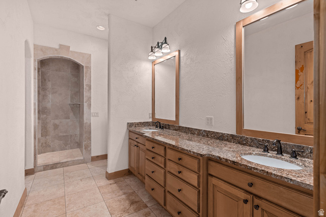 2464 East Granite Way St. George, UT 84790 - Photo 83 of 106 Bathroom with double vanity, a tile shower, a textured wall, light tile patterned floors, and recessed lighting