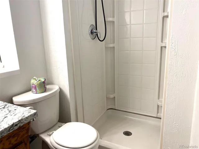 a bathroom with a granite countertop toilet and a sink