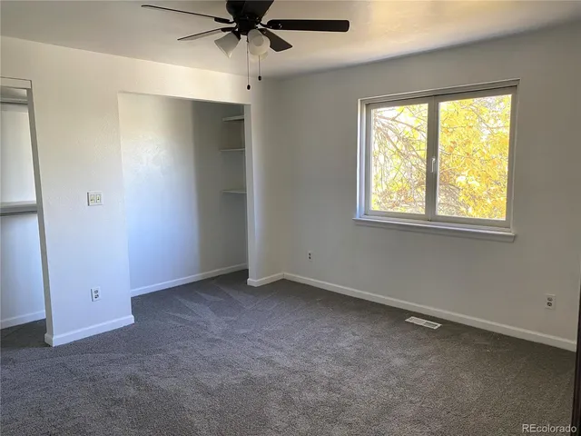 an empty room with a window and a fan