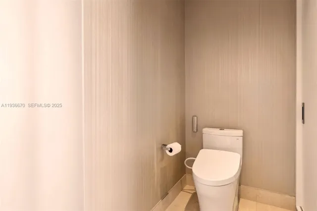 a white toilet sitting next to a white wall