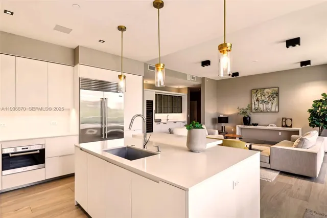 a kitchen with stainless steel appliances kitchen island granite countertop a sink a stove and a wooden floors