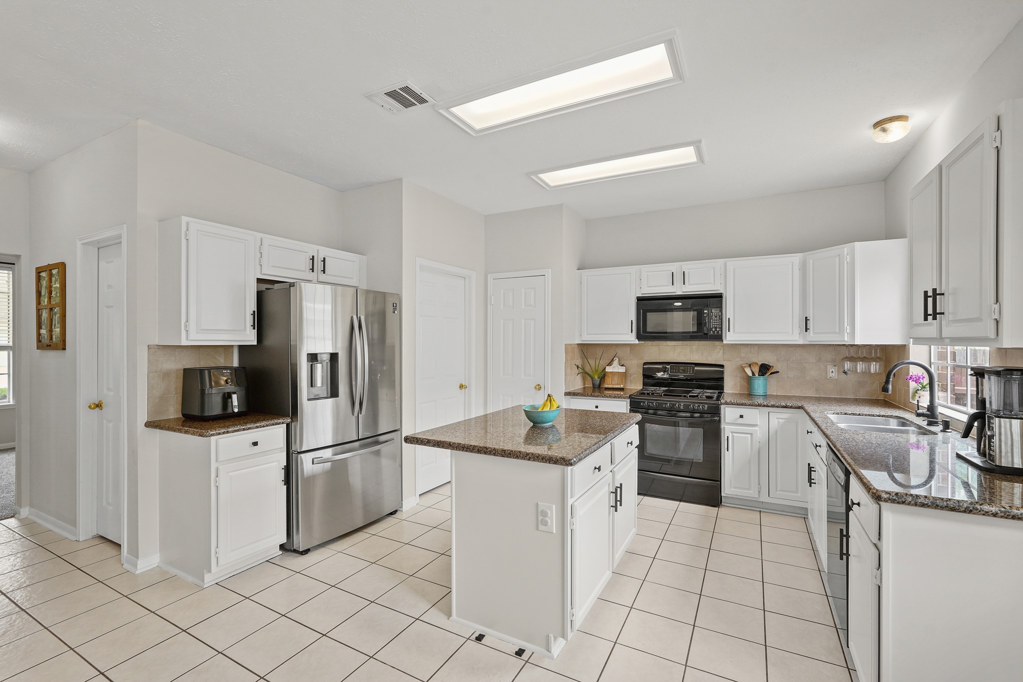 16114 Kintyre Point Road Houston, TX 77095 - Photo 20 of 44 Spacious kitchen with modern stainless steel appliances, granite countertops, and ample white cabinetry. It features a central island, tiled flooring, and plenty of natural light.