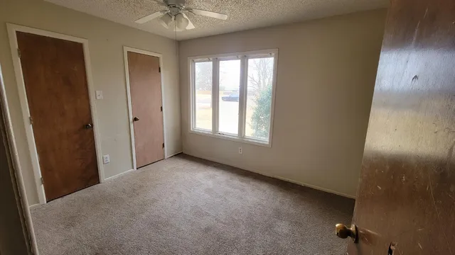 an empty room with a window and a ceiling fan
