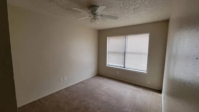 an empty room with a fireplace and a ceiling fan