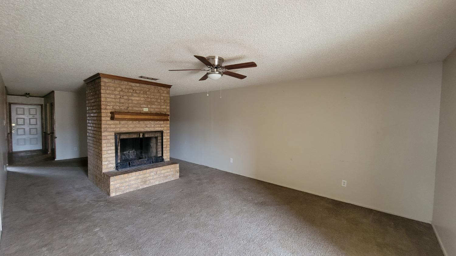 1107 80th Street, Unit B Lubbock, TX 79423 - Photo 8 of 12 an empty room with a fireplace and a ceiling fan