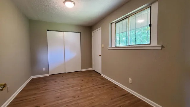 an empty room with wooden floor and windows