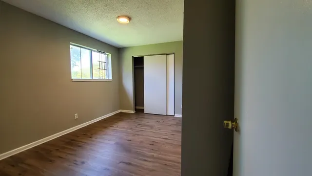 an empty room with wooden floor and windows