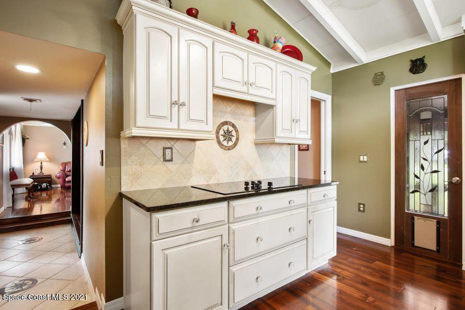 907 Santa Cruz Road Cocoa Beach, FL 32931 - Photo 7 of 30 a kitchen with granite countertop white cabinets and wooden floor