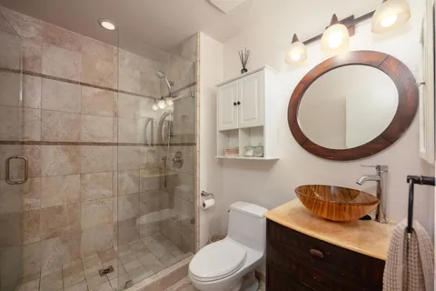 a bathroom with a granite countertop toilet a sink and a mirror