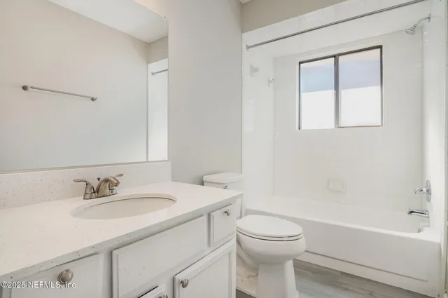 a bathroom with a granite countertop toilet a sink and a bathtub