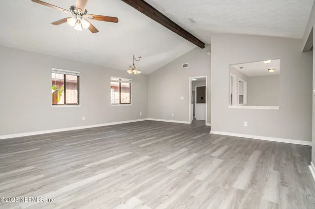 a view of empty room with wooden floor and fan
