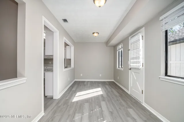 a view of empty room with wooden floor and fan
