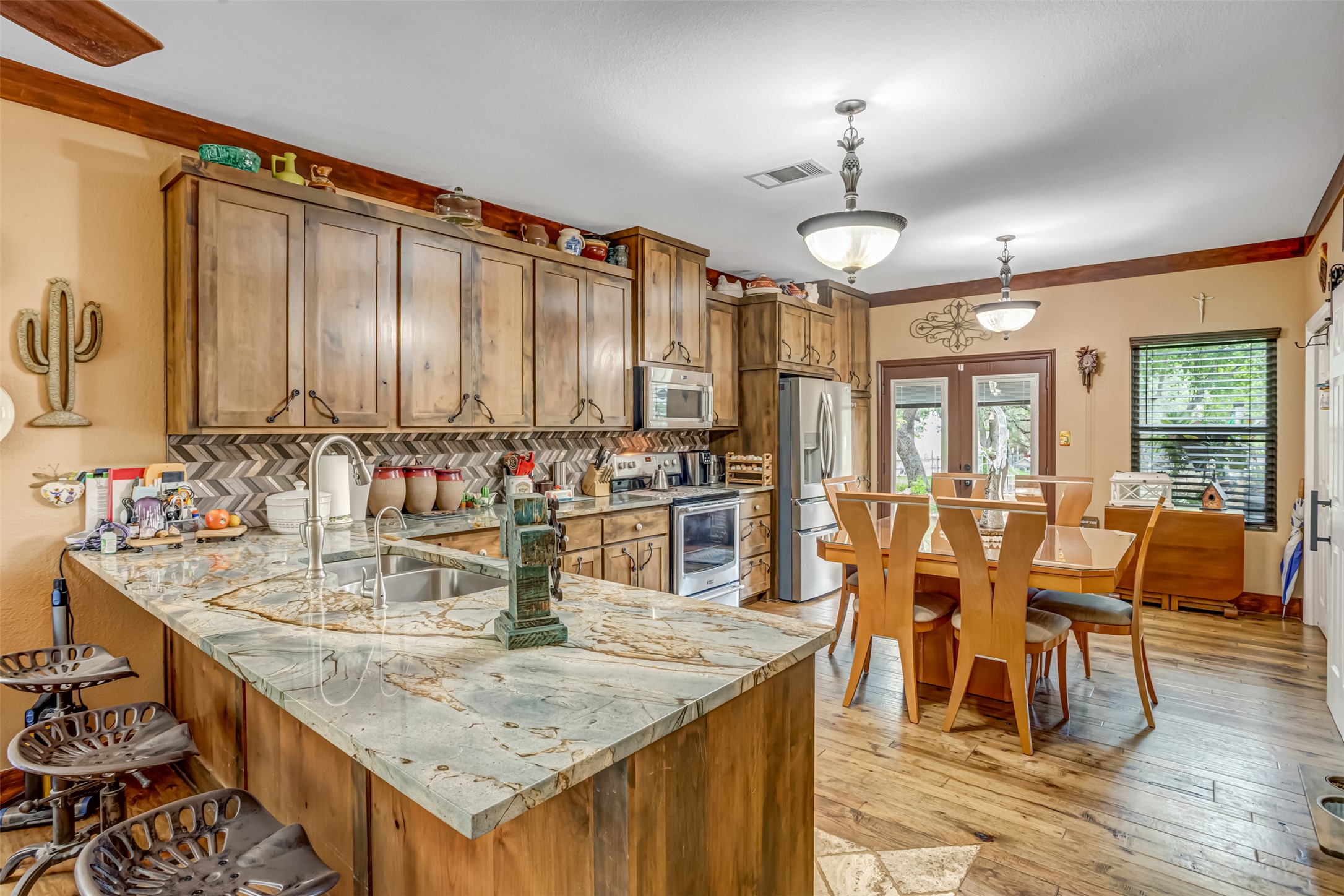 4909 Lookout Ridge Drive Marble Falls, TX 78654 - Photo 12 of 39 The kitchen features extensive wooden cabinetry, a granite island with an undermount sink, and a herringbone pattern tile backsplash