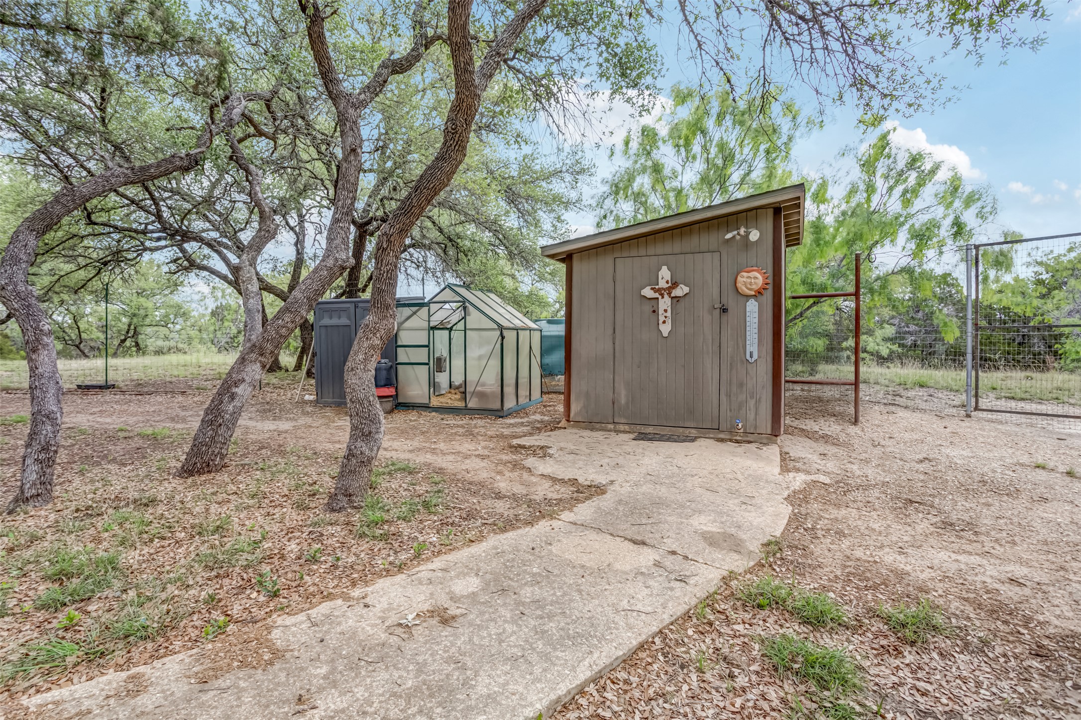 4909 Lookout Ridge Drive Marble Falls, TX 78654 - Photo 39 of 39 The property features a storage shed with a sloped roof and a separate greenhouse