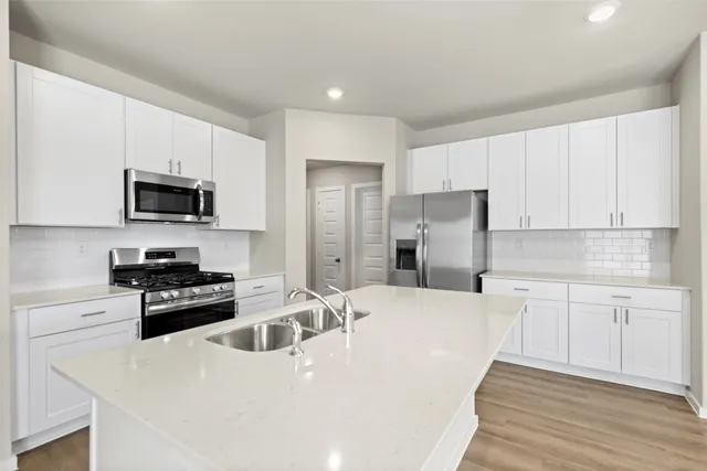 a kitchen with stainless steel appliances a stove a sink a microwave and cabinets