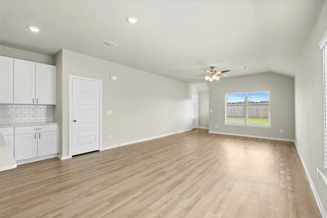 a view of an empty room with a window and wooden floor