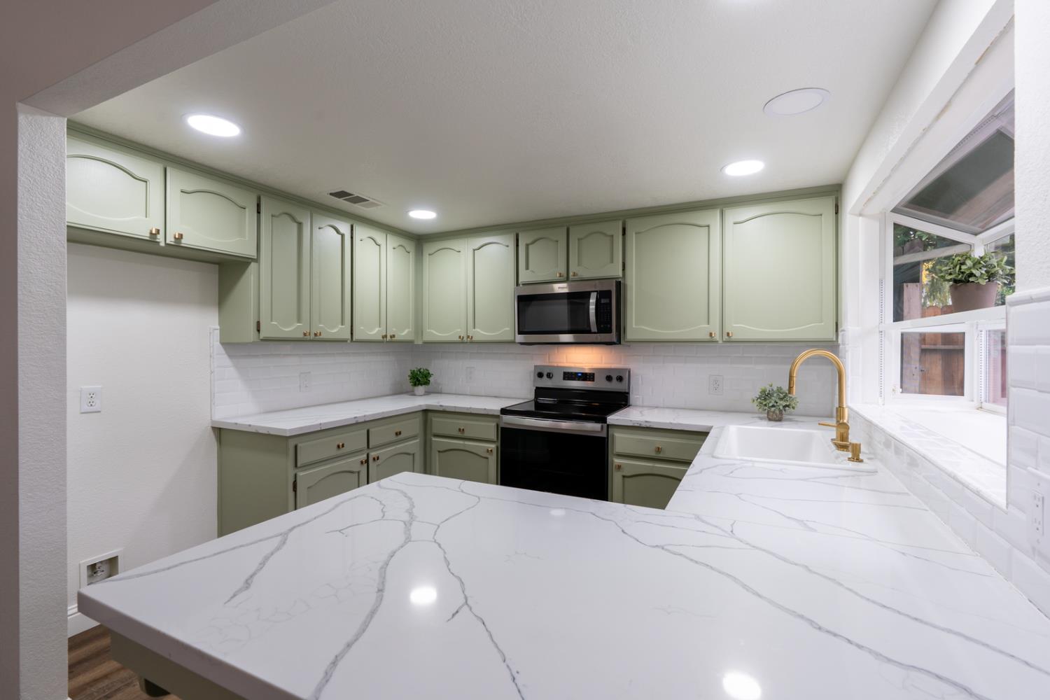 899 La Jolla Way Merced, CA 95348 - Photo 25 of 51 a kitchen with a sink a stove a refrigerator cabinets and a dining table