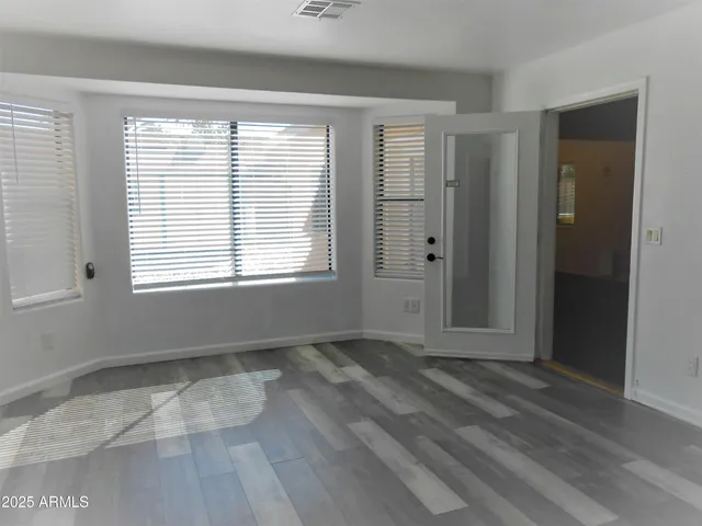a view of an empty room with wooden floor and a window