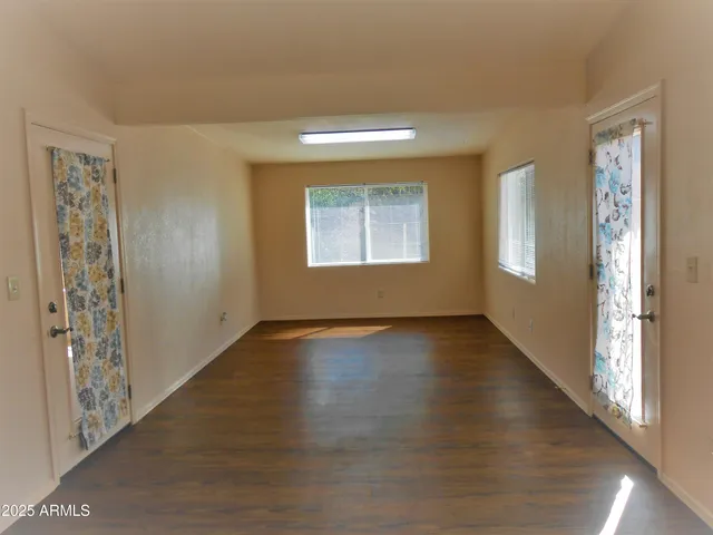 a view of an empty room with window and wooden floor