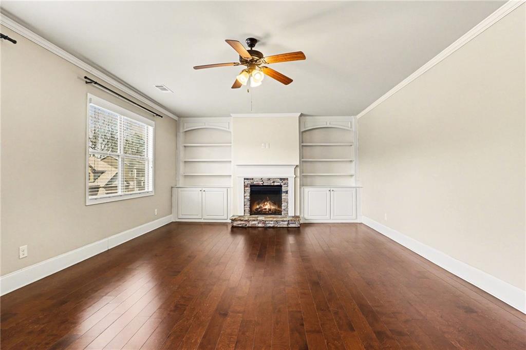 4208 Amberleaf Walk Lilburn, GA 30047 - Photo 9 of 33 an empty room with wooden floor fireplace and windows