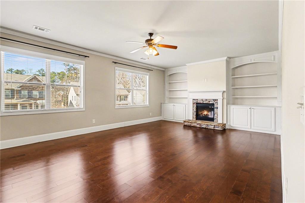 4208 Amberleaf Walk Lilburn, GA 30047 - Photo 10 of 33 an empty room with wooden floor fireplace and windows