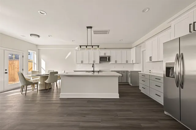 a large kitchen with kitchen island a white counter space a sink appliances and cabinets