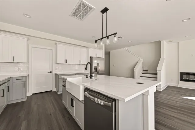 a kitchen with a sink a stove a refrigerator and white cabinets