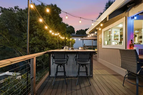 a roof deck with table and chairs with wooden floor and fence